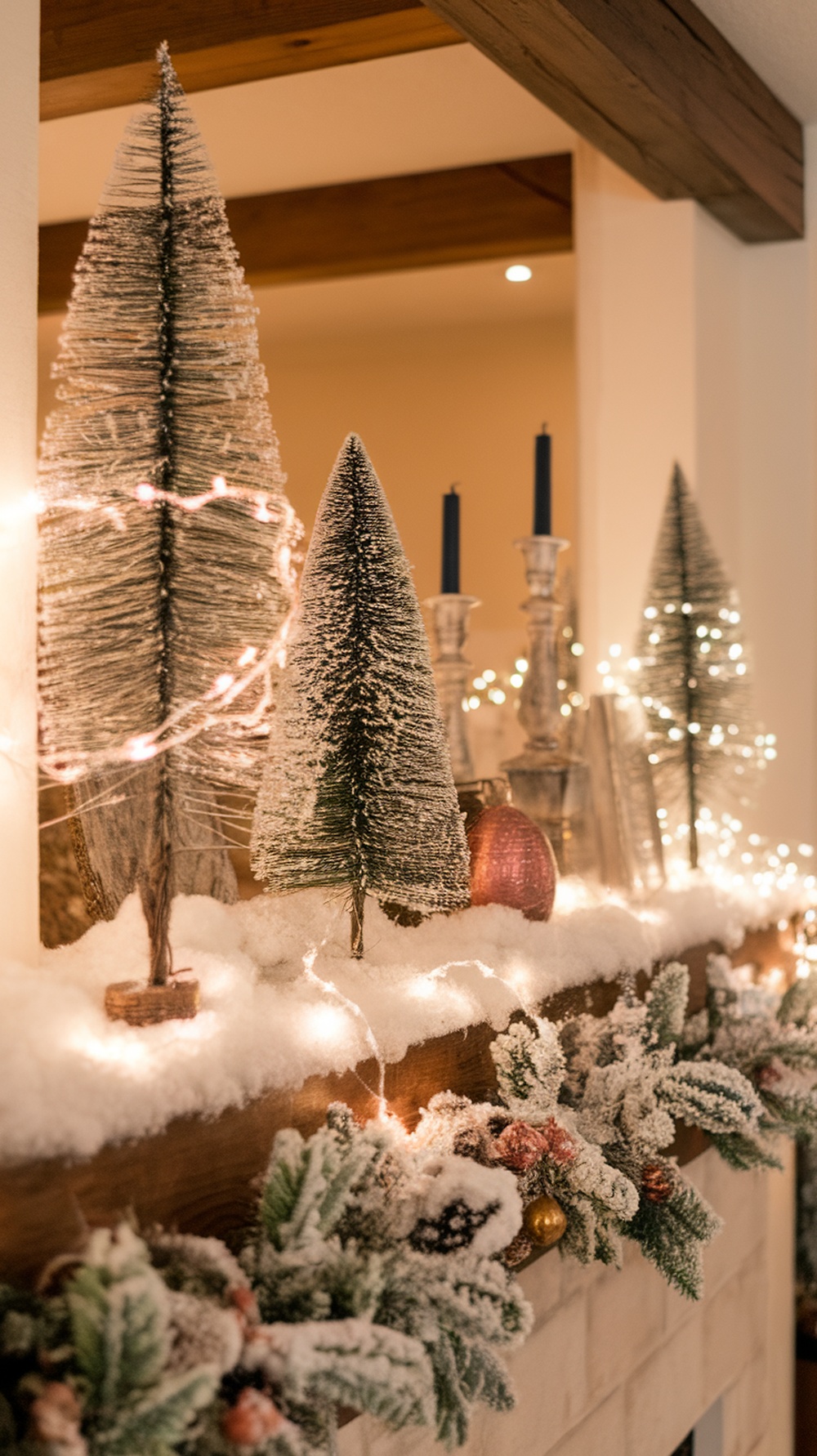 A beautifully decorated mantle with frosted trees, twinkling lights, and a snowy garland.