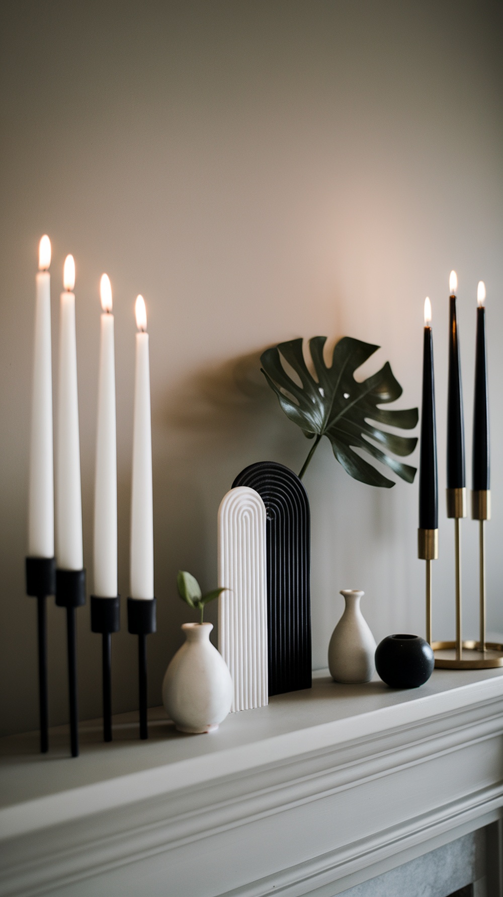A stylish monochrome Christmas mantle decoration featuring black and white candles, vases, and a decorative sculpture.